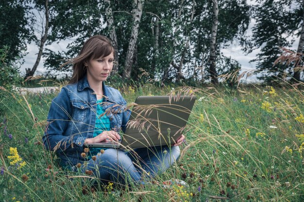 Ragazza con il computer portatile in un campo