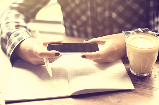 Ragazza con il diario del cellulare e la tazza di caffè