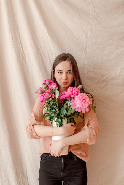 Ragazza con il mazzo delle peonie sul fondo del tessuto