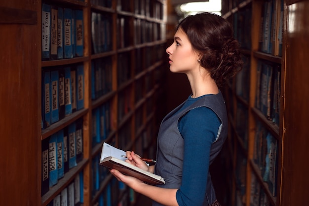 Ragazza con il taccuino seleziona il libro di testo in libreria.