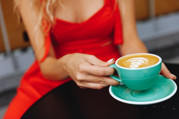 Ragazza con in mano una tazza di cappuccino color turchese