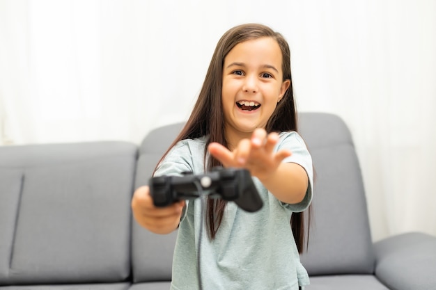 Ragazza con joystick. Bambina eccitata che gioca al videogioco e sorride