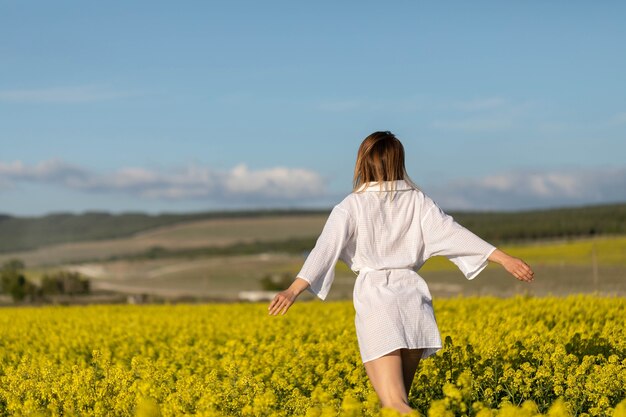 Ragazza con la camicia bianca che corre nel campo di fiori gialli