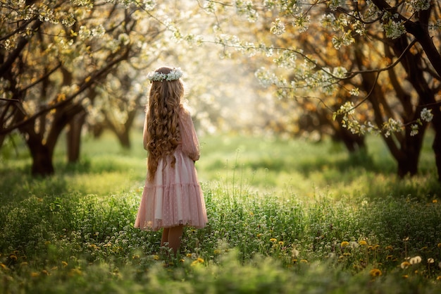 Ragazza con la corona floreale in un giardino fiorito