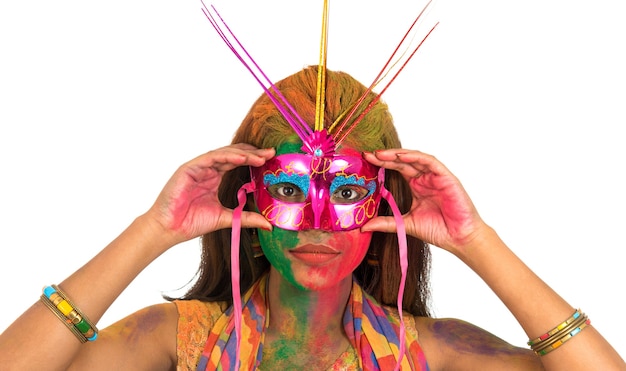 Ragazza con la faccia colorata che tiene la maschera di carnevale e celebra holi.