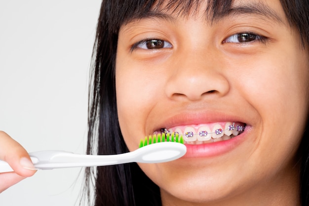 Ragazza con la mano dei denti delle parentesi graffe che tiene spazzolino da denti che sorride e felice