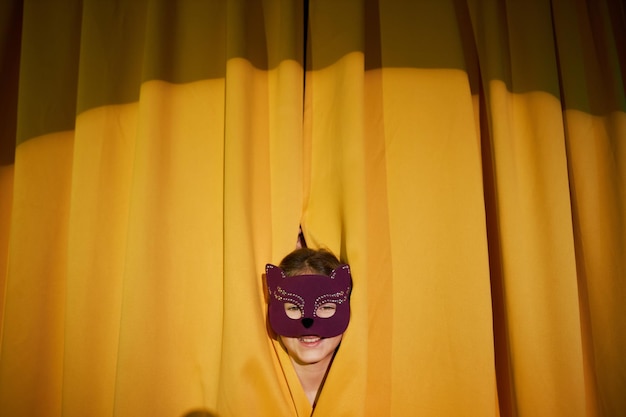 Ragazza con la maschera che sbircia sul palco