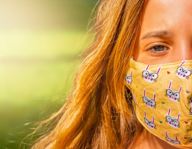 ragazza con la maschera per il viso cammina nel parco durante il giorno.