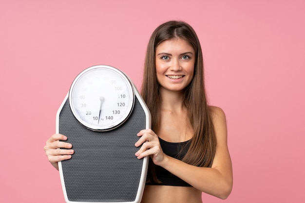 Ragazza con la pesa sopra fondo rosa isolato