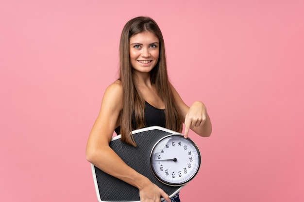 Ragazza con la pesa sopra il rosa isolato