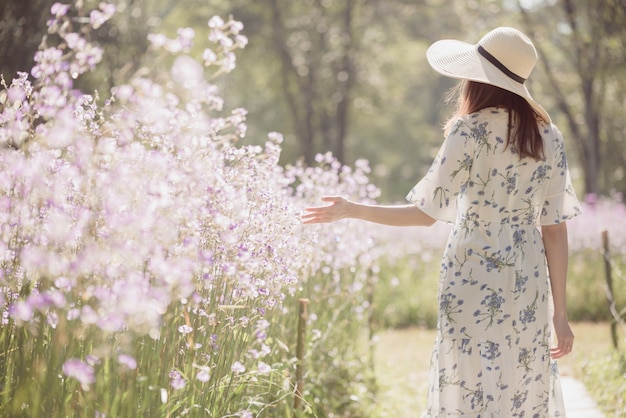 Ragazza con la schiena e cappello di paglia in un campo di fiori