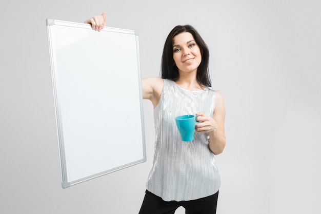 Ragazza con la tazza del turchese e supporti del bordo magnetico isolati sulla maglietta leggera