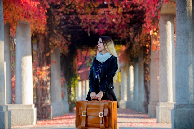 Ragazza con la valigia in vicolo dell'uva rossa