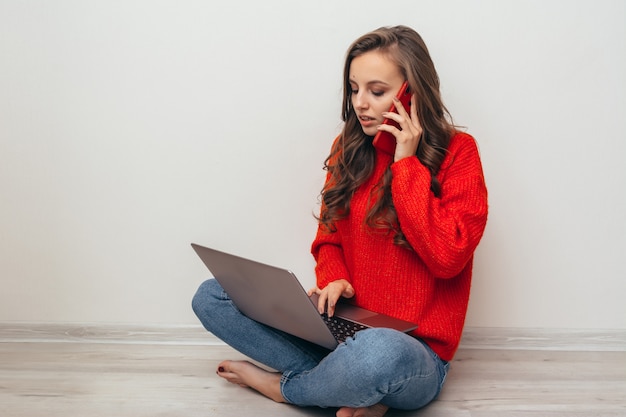 Ragazza con laptop e telefono a casa.