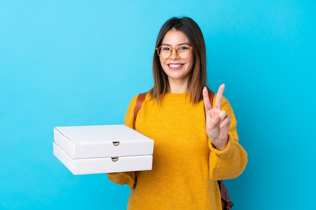 Ragazza con le pizze sopra la parete blu