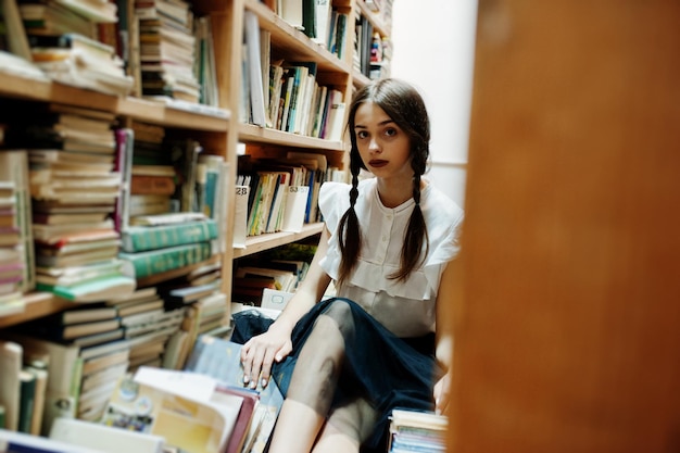 Ragazza con le trecce in camicetta bianca alla vecchia biblioteca