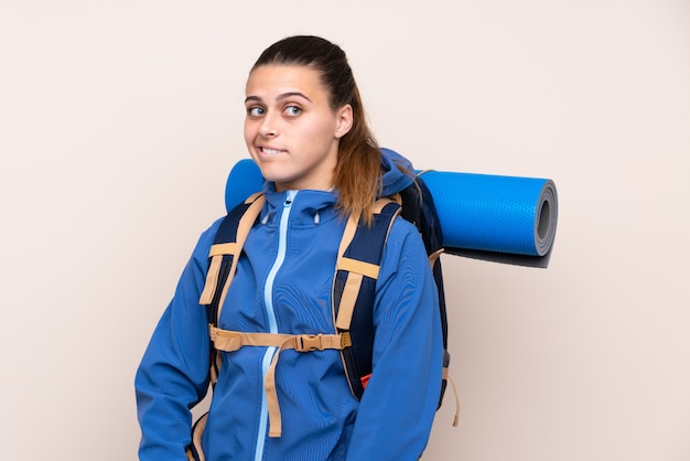 Ragazza con lo zaino dell'alpinista sopra la parete isolata