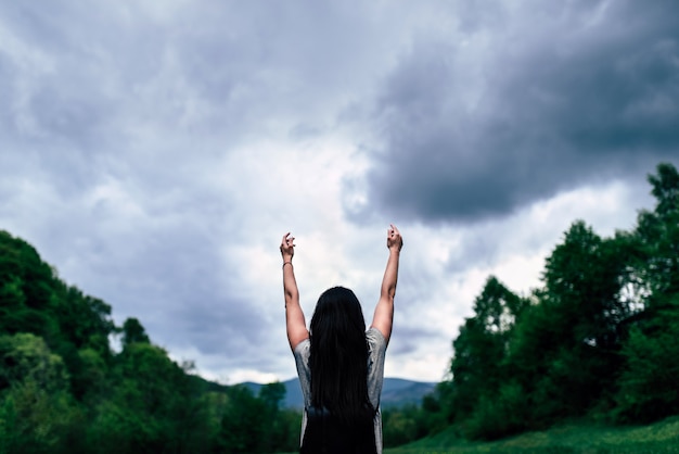 Ragazza con lo zaino in montagna con il cielo nuvoloso