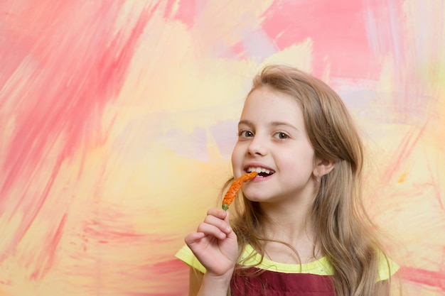 Ragazza con lunghi capelli biondi che mangia peperoncino rosso