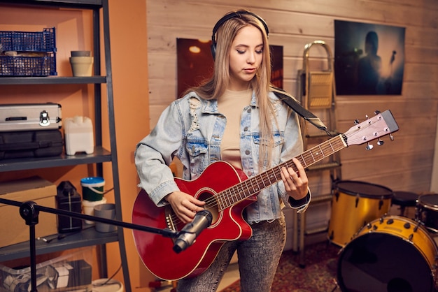 Ragazza con lunghi capelli biondi che suona la chitarra elettrica in studio