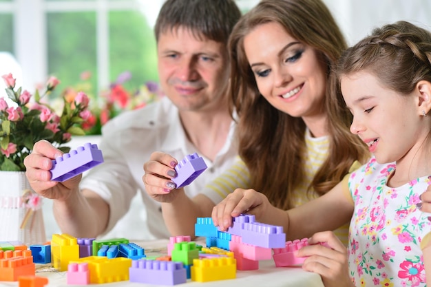 Ragazza con madre e padre che giocano con blocchi di plastica colorati