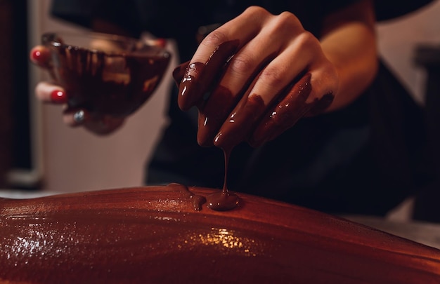 Ragazza con maschera per il corpo al cioccolato nel salone di bellezza