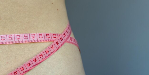 ragazza con nastro di misurazione di colore rosa sulla vita fitness perdere peso concetto