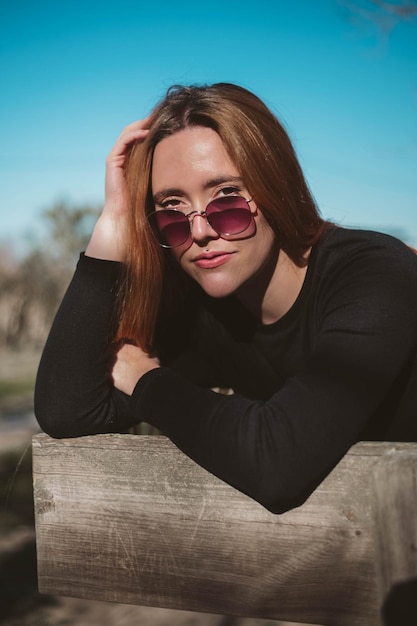 Ragazza con occhiali da sole rosa che guarda l'obbiettivo