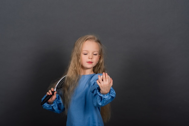 Ragazza con pettine aggrovigliato capelli e spazzola per capelli sensazione di dolore, studio