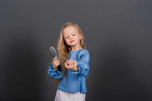 Ragazza con pettine aggrovigliato capelli e spazzola per capelli sensazione di dolore, studio