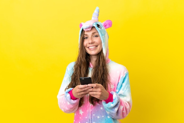 Ragazza con pigiama unicorno su sfondo isolato inviando un messaggio con il cellulare