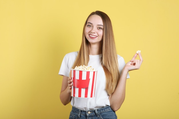 Ragazza con popcorn su sfondo colorato guarda un film d film