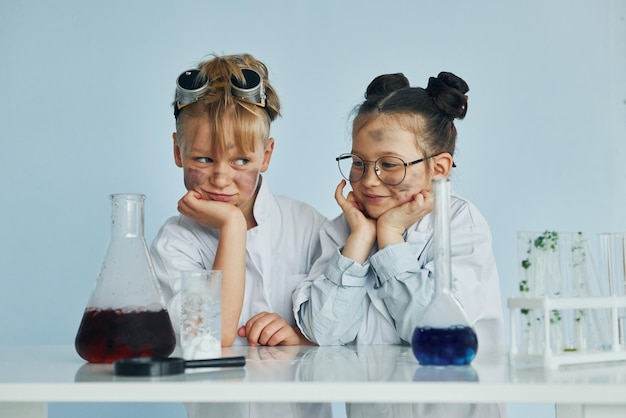 Ragazza con ragazzo che lavora insieme Bambini in camice bianco interpreta uno scienziato in laboratorio utilizzando attrezzature