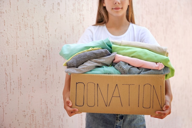 Ragazza con scatola di donazione con vestiti estivi.