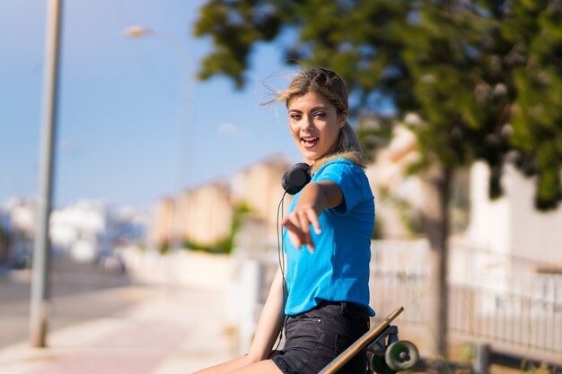 ragazza con skate all'aperto sorpreso e che punta davanti