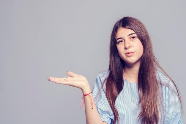 Ragazza con sopracciglia folte e lunghi capelli scuri che tiene il palmo della mano