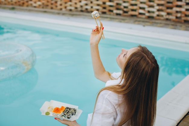 Ragazza con sushi a bordo piscina