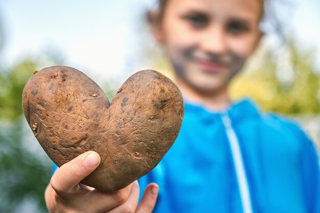 ragazza con tubero di patata a forma di cuore all'aperto.