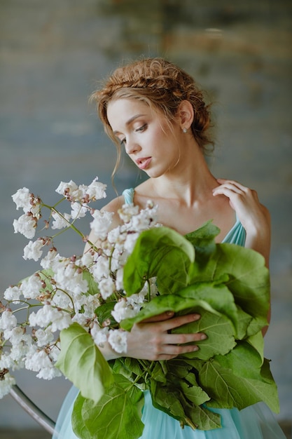 Ragazza con un bel mazzo di fiori in un vestito blu