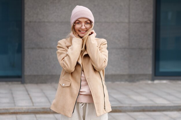 Ragazza con un bennie rosa che sorride felicemente in strada