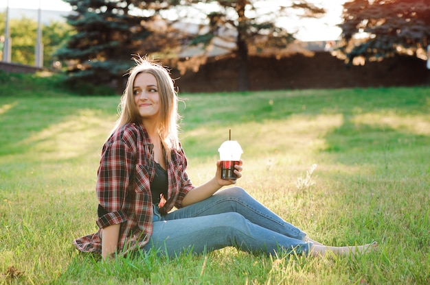 Ragazza con un bicchiere di succo su un prato verde.