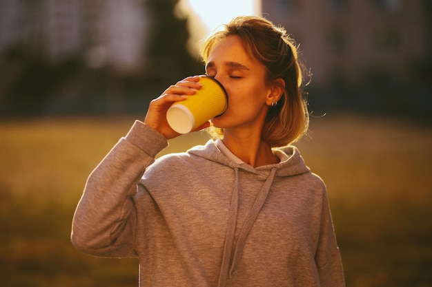 ragazza con un caffè ragazza beve lat da un bicchiere di carta per strada elaborazione di foto d'epoca