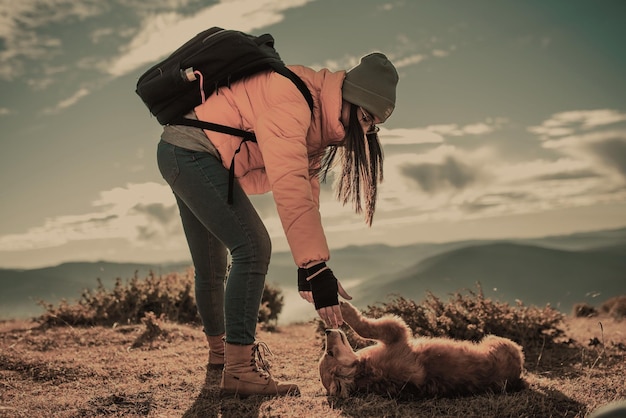 Ragazza con un cane gioca in montagna. Atmosfera autunnale. In viaggio con un animale domestico. Donna e il suo cane in posa all'aperto.