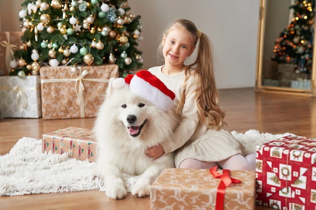 Ragazza con un cane vicino all'albero di Natale sulla scena di natale