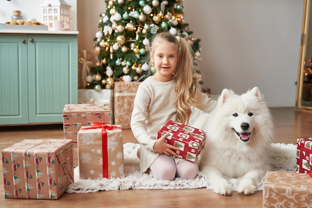 Ragazza con un cane vicino all'albero di Natale sulla scena di natale