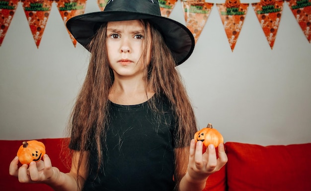 Ragazza con un cappello di Halloween con le zucche nelle sue mani