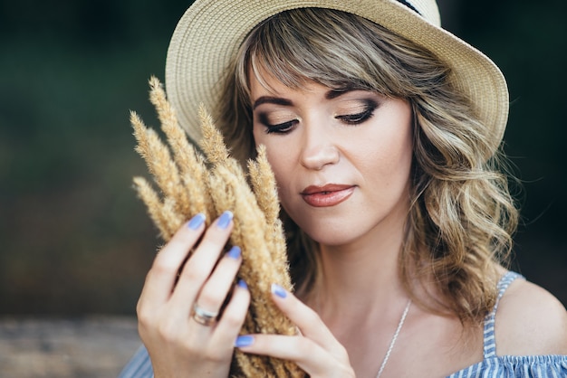 Ragazza con un cappello e spighe di grano nelle sue mani