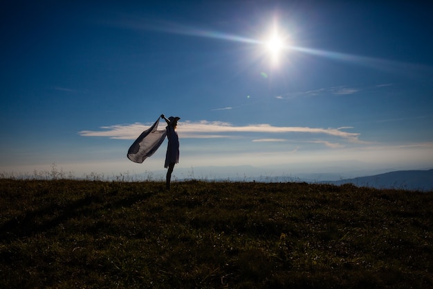 Ragazza con un fazzoletto sollevato, che si gode la luce del sole in cima alla montagna