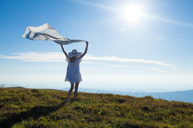 Ragazza con un fazzoletto sollevato, che si gode la luce del sole in cima alla montagna