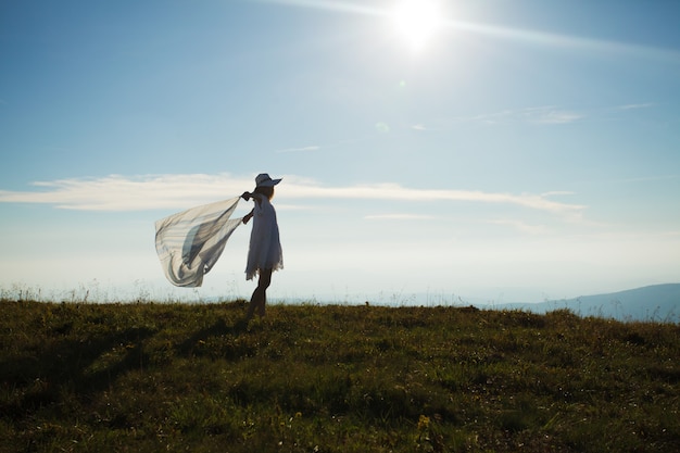 Ragazza con un fazzoletto sollevato, che si gode la luce del sole in cima alla montagna